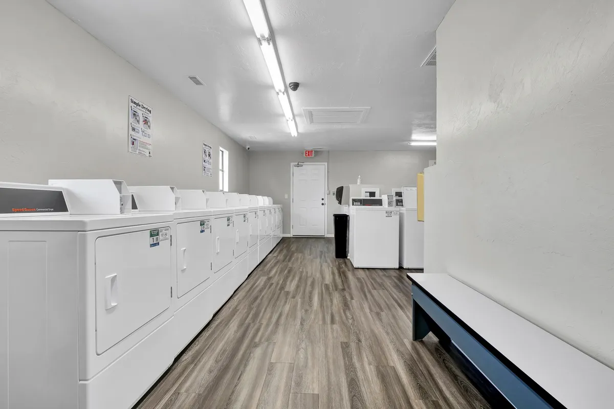 A practical community laundry room fitted with a row of washing machines and dryers, plus a folding bench. The space is clean and functional, emphasizing convenience and the everyday comforts available to guests.