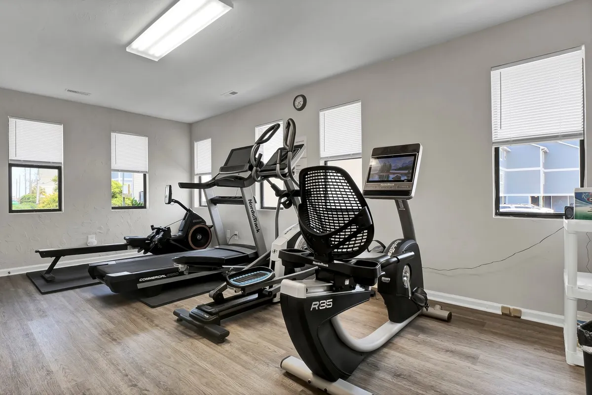 A modern, well-lit gym space featuring a variety of exercise equipment such as treadmills and bikes. Large windows let in natural light and provide a motivating atmosphere. The scene suggests an energetic, health-focused environment ideal for guests looking to stay active during their stay.